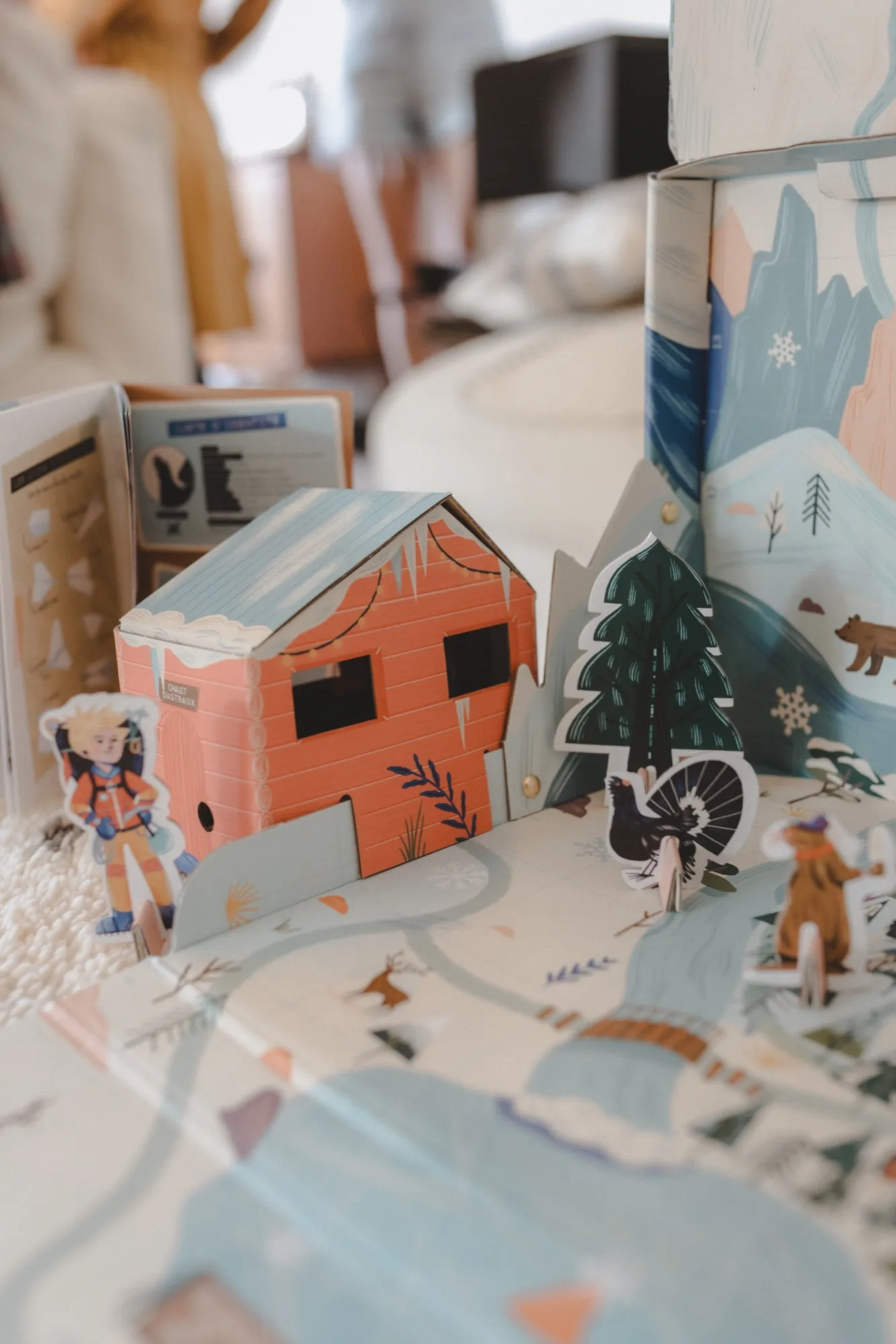 Calendrier de l'Avent En Cavale déplié en plateau de jeu, avec chalet et personnages en carton