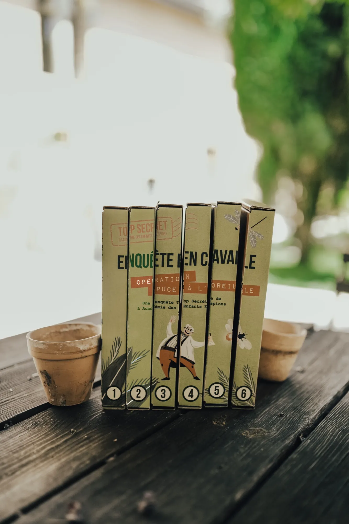 Six étuis numérotés de l'enquête En Cavale « Opération puce à l'oreille », alignés sur une table en bois